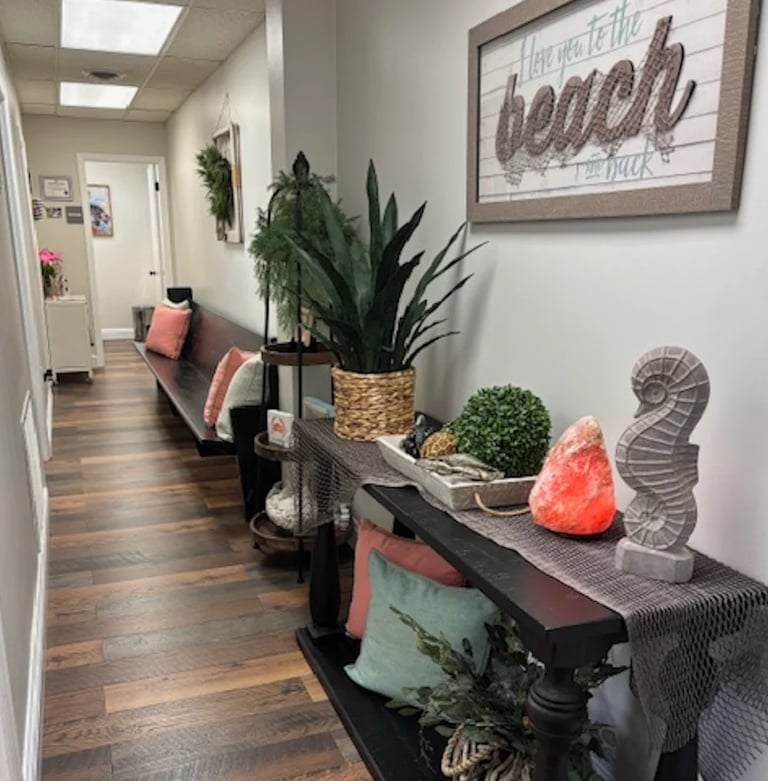 Modern hallway with wooden floors, potted plants on shelves, decorative items, and a inspirational sign on the wall